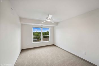 an empty bedroom with a window and a ceiling fan